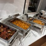 Various dishes in buffet trays with spareribs and corn